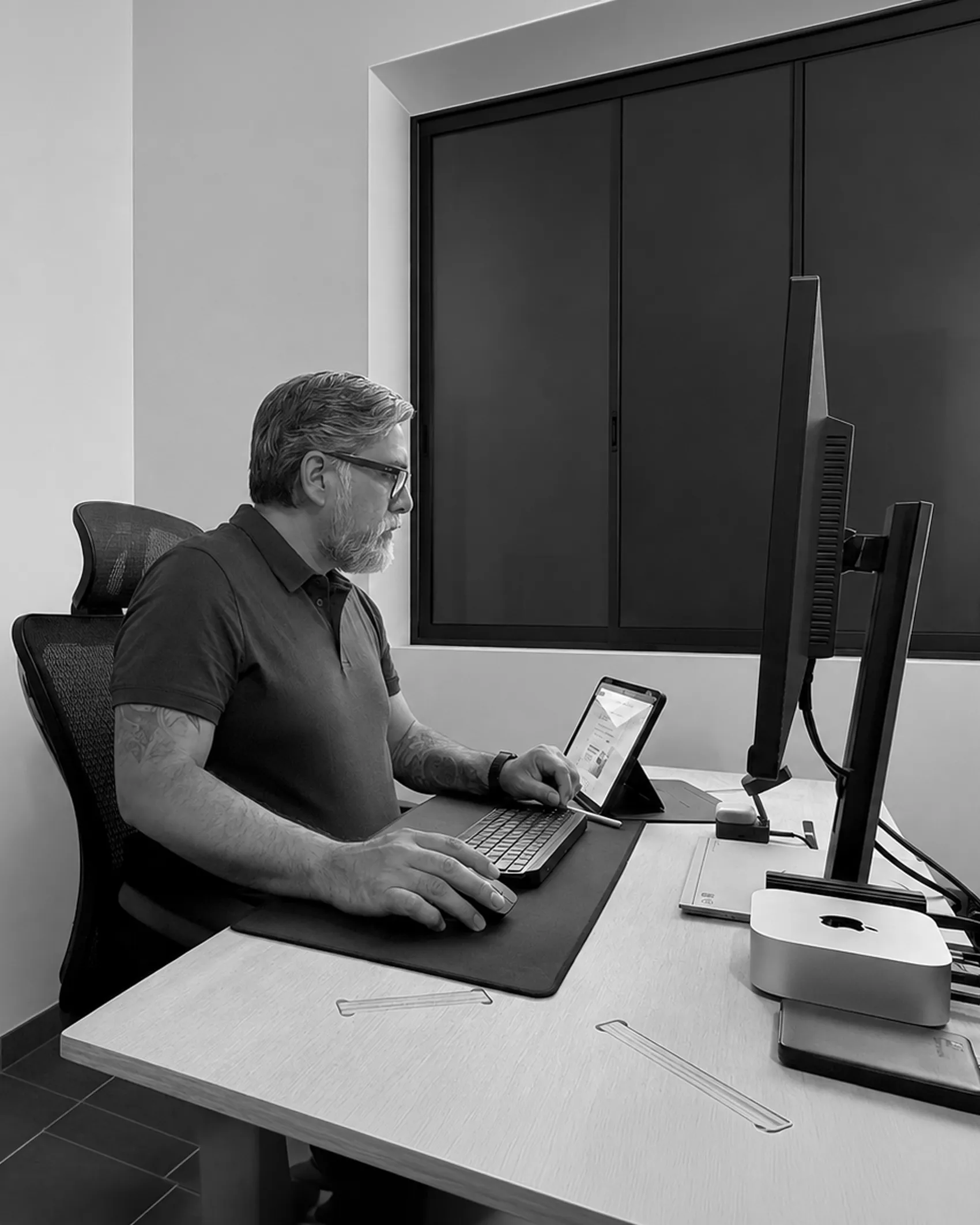 Consultor de ideasinlab en su escritorio, revisando datos en una tablet junto al monitor